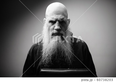 Portrait of angry mature bald bearded man with dramatic shot in black and white 60738203