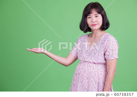 Portrait of beautiful Asian pregnant woman showing something Portrait of beautiful Asian pregnant woman showing something 60738357