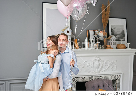 Loving family. Mom and dad hugging little daughter . Parents and baby child having fun near Christmas tree and white fireplace indoors. Merry Christmas and Happy New Year. Cheerful pretty people. 60739437