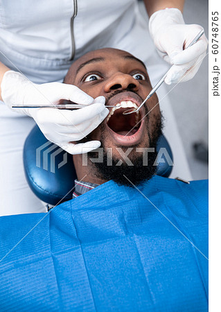 Young african-american man visiting dentist's office, looks scared 60748765