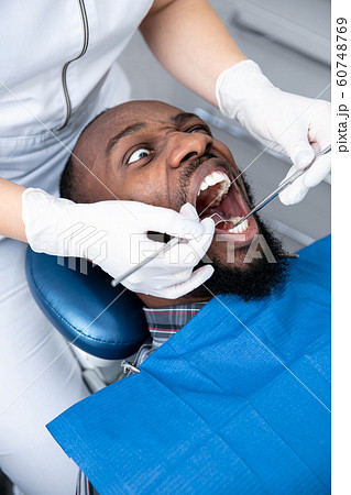 Young african-american man visiting dentist's office, looks scared 60748769