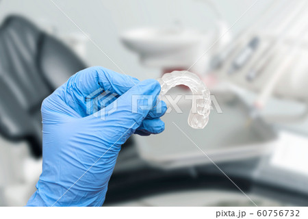 Hand in glove holding invisible aligner 60756732