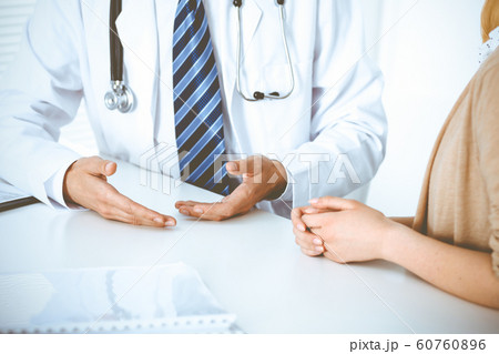 Doctor and patient woman discussing something at the desk in hospital office. Concepts of medical ethics and helping people in medicine Doctor and patient woman discussing something at the desk in hospital office. Concepts of medical ethics and helping people in medicine 60760896