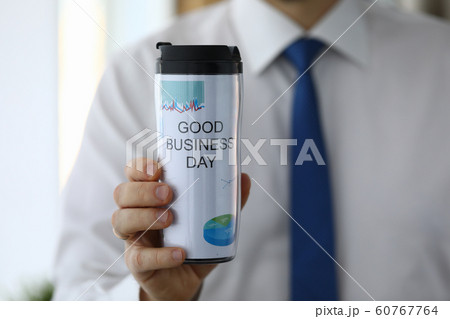 Man hold in hand thermal flask with hot beverage closeup 60767764