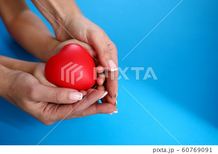 Mother and daughter hold red heart against blue Mother and daughter hold red heart against blue 60769091