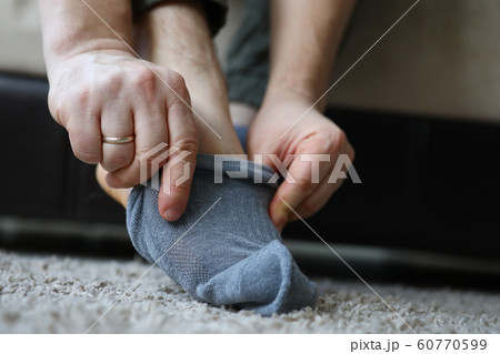 Man at home in morning puts gray socks on his leg Man at home in morning puts gray socks on his leg 60770599