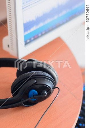 Big black headphones lie on the wooden desktop of 60770642