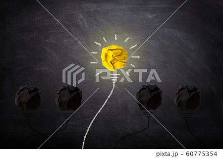 Yellow crumpled paper ball light bulb lighting grow around on chalkboard. Yellow crumpled paper ball light bulb lighting grow around on chalkboard. 60775354