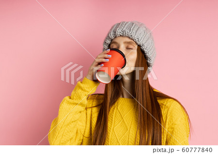 Redhead woman holding disposable cup of coffee Redhead woman holding disposable cup of coffee 60777840
