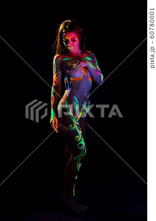Female with UV light bodyart in the dark 60780001