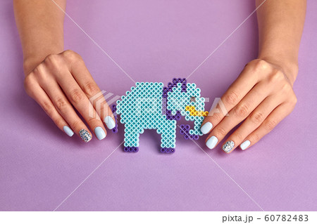 Blue toy elephant and female manicure on a violet 60782483