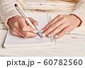 Woman writing in spiral notepad placed on wooden 60782560