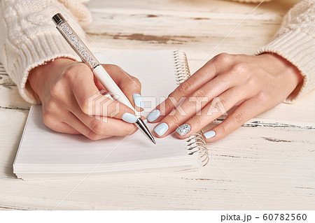 Woman writing in spiral notepad placed on wooden Woman writing in spiral notepad placed on wooden 60782560
