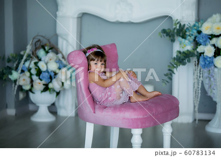 A young lady in a room with candles is having fun and smiling on a pink upholstered chair A young lady in a room with candles is having fun and smiling on a pink upholstered chair 60783134