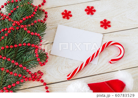 Empty greeteing card and sweet candy cane on a wooden table near a fir branch. 60783529
