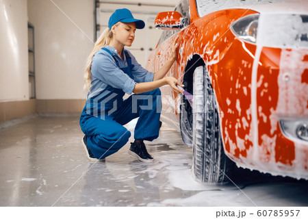 Female washer with brush cleans wheel, car wash Female washer with brush cleans wheel, car wash 60785957