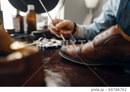Bootmaker with brush tints shoes, footwear repair Bootmaker with brush tints shoes, footwear repair 60786762