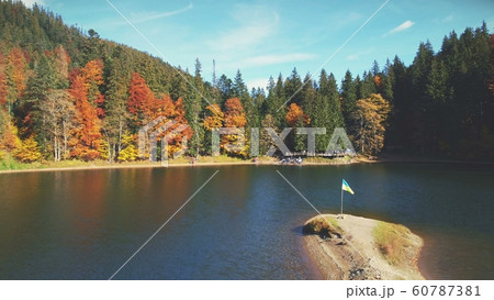 tourists wander along lake sandy bank by mixed forests 60787381