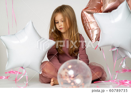 Portrait of sad Caucasian blond little girl with colorful balloons over white background 60789735