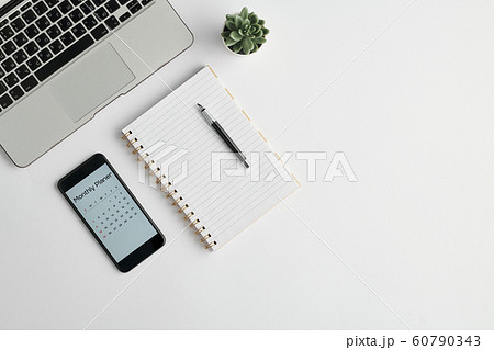 Notebook with pen, monthly planner in the phone, plant in flowerpot and laptop Notebook with pen, monthly planner in the phone, plant in flowerpot and laptop 60790343
