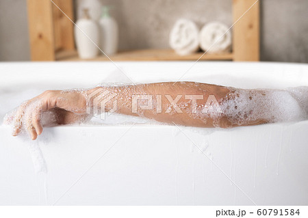 Arm of young man relaxing in white porcelain bath with foam Arm of young man relaxing in white porcelain bath with foam 60791584