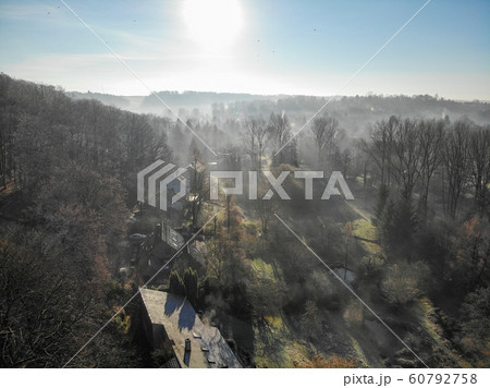 Aerial view of forest and farmland during foggy and cold winter morning with blue sky facing the sun 60792758