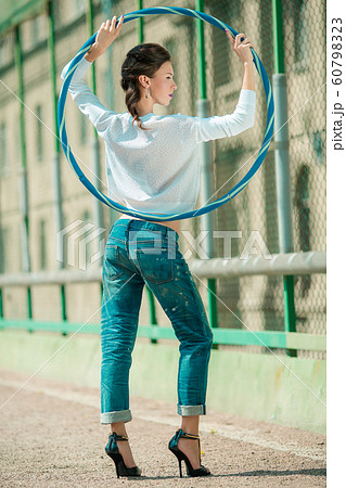 Stylish girl with a thin waist in jeans on a sports hoop Stylish girl with a thin waist in jeans on a sports hoop 60798323