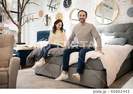 Happy couple trying new bed in furniture salon Happy couple trying new bed in furniture salon 60802443