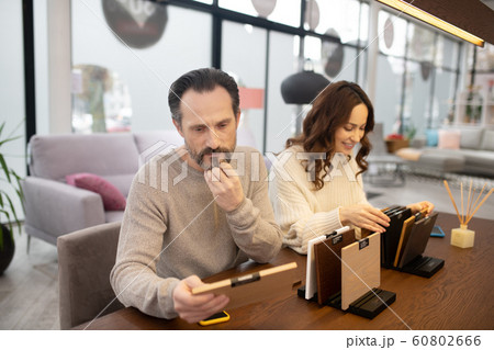 Man and woman in light sweaters looking at wood samples 60802666