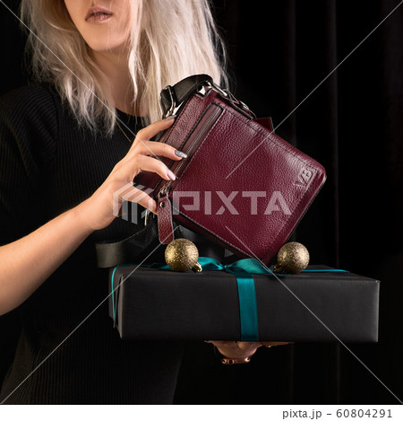 Modern burgundy, leather, men bagin a female hand. girl holds a gift, 1:1 copy space for text and design. Modern burgundy, leather, men bagin a female hand. girl holds a gift, 1:1 copy space for text and design. 60804291