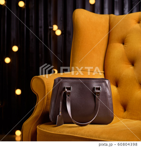 brown leather bag for business woman, on the yellow armchair. 1:1 copy space for text and design. 60804398