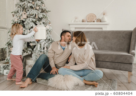 Family Christmas morning in a bright minimalistic living room near the Christmas tree. 60804404