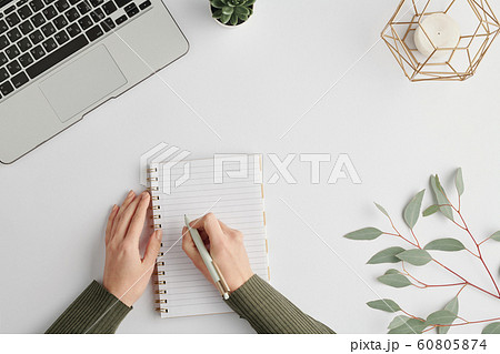 Hands of young businesswoman holding pen over blank page of notebook Hands of young businesswoman holding pen over blank page of notebook 60805874