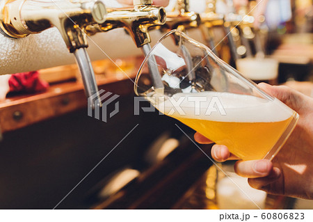 close-up of barman hand at beer tap pouring a draught lager beer. close-up of barman hand at beer tap pouring a draught lager beer. 60806823