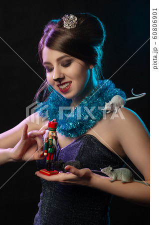 girl in Mouse Queen costume plays with Nutcracker toy on black background 60806901