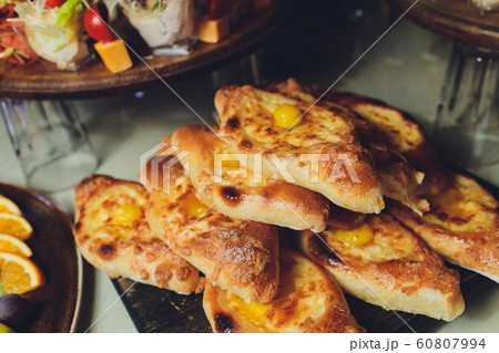 Process of cooking traditional adjarian georgian and armenian cuisine, hachapuri khachapuri with suluguni cheese and egg yolk on a wooden table with chief's hands in the background. Process of cooking traditional adjarian georgian and armenian cuisine, hachapuri khachapuri with suluguni cheese and egg yolk on a wooden table with chief's hands in the background. 60807994