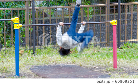 公園の鉄棒で逆上がりをする子供の写真素材