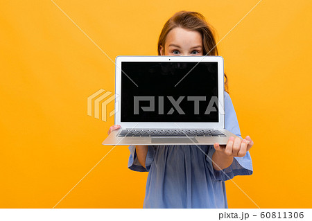 charming girl peeks out at a laptop with a mockup on a yellow background charming girl peeks out at a laptop with a mockup on a yellow background 60811306
