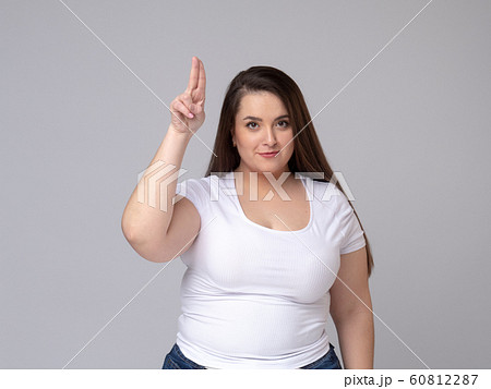 Portrait of serious plus size woman standing saluting with hand near head Portrait of serious plus size woman standing saluting with hand near head 60812287