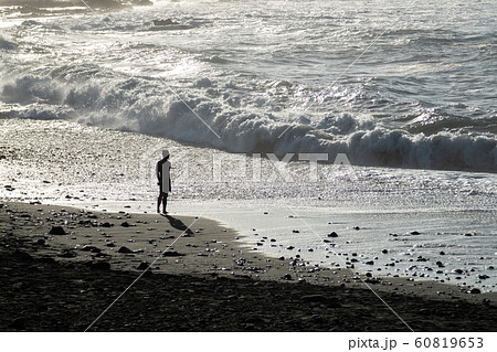 A man is standing on the beach on a sunny evening and looking at the sea. 60819653