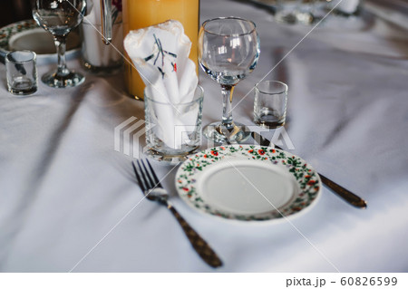 set of empty glasses and plates with Cutlery on a white tablecloth on the table in the restaurant set of empty glasses and plates with Cutlery on a white tablecloth on the table in the restaurant 60826599