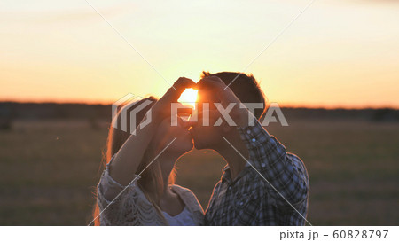 A couple in love makes a heart shape from their hands and kisses. A couple in love makes a heart shape from their hands and kisses. 60828797