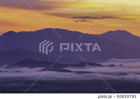 A morning view of a mist-covered mountain and the sun rising from the mountains. 60830793