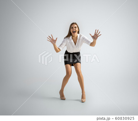 Caucasian woman in office clothes catching ball isolated on grey studio background 60830925