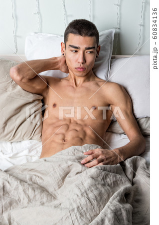 Young handsome man rest in bed. Sexy naked guy is 60834136