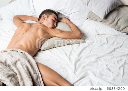 Young handsome man rest in bed. Sexy naked guy is 60834200