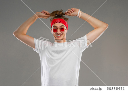 guy with stylish glasses and a bandana straightens the tail on his head on a gray background guy with stylish glasses and a bandana straightens the tail on his head on a gray background 60836451