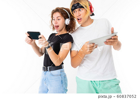 emotional girl plays a game on the phone and the guy with the tablet in his hands peeps at the girl 60837052
