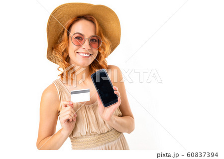 cute tourist in a hat dressed in a summer dress shows a phone and a credit card with a mockup on a cute tourist in a hat dressed in a summer dress shows a phone and a credit card with a mockup on a 60837394