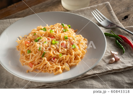 The noodles are in a round white plate placed on a The noodles are in a round white plate placed on a 60843318
